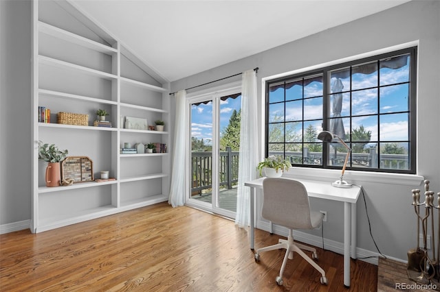 office with wood finished floors, lofted ceiling, and built in shelves