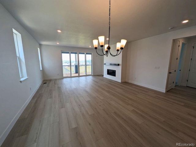 8326 Cokedale Cir, Littleton, CO 80125 - unfurnished living room featuring wood finished floors, baseboards, a chandelier, recessed lighting, and a glass covered fireplace