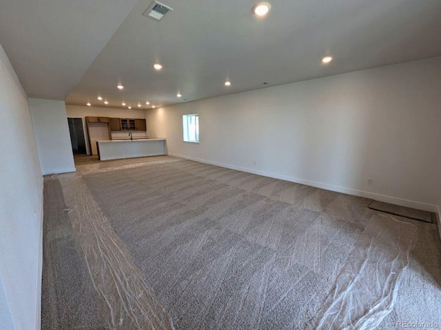 8326 Cokedale Cir, Littleton, CO 80125 - unfurnished living room featuring light colored carpet, recessed lighting, baseboards, and a sink