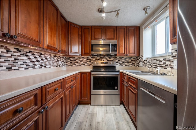 kitchen with tasteful backsplash, sink, stainless steel appliances, and light hardwood / wood-style flooring