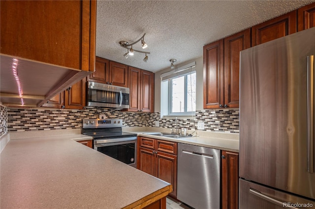 kitchen featuring a textured ceiling, sink, appliances with stainless steel finishes, and tasteful backsplash