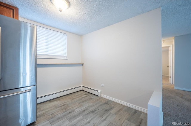 spare room featuring a textured ceiling, light wood-type flooring, and baseboard heating