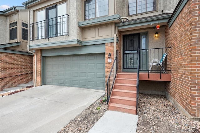doorway to property featuring stucco siding, concrete driveway, brick siding, and a garage