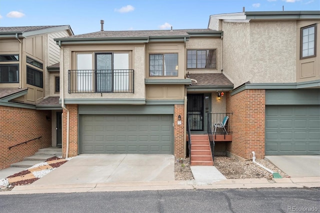 7450 W Coal Mine Ave Unit D, Littleton, CO 80123 - view of property with an attached garage, driveway, stucco siding, and brick siding