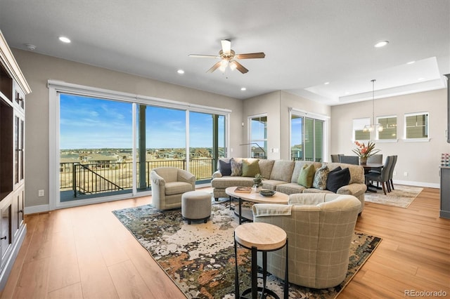 living area with light wood-type flooring, ceiling fan with notable chandelier, baseboards, and recessed lighting
