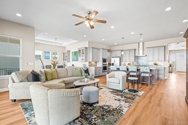 living room featuring light wood-type flooring, a ceiling fan, and recessed lighting