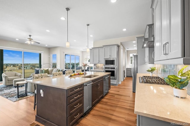 kitchen with stainless steel appliances, tasteful backsplash, light wood finished floors, and a sink