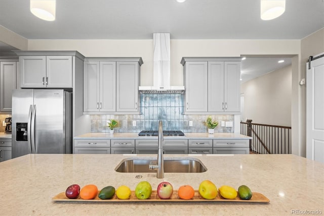 kitchen featuring a sink, wall chimney range hood, gray cabinets, and stainless steel appliances