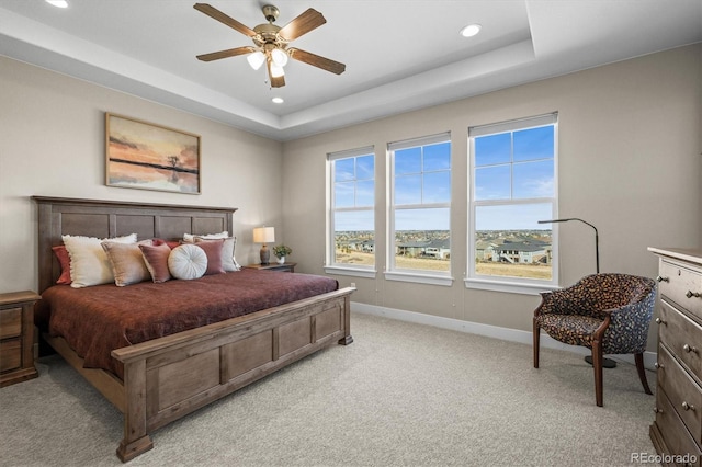 bedroom featuring baseboards, light carpet, recessed lighting, a ceiling fan, and a tray ceiling