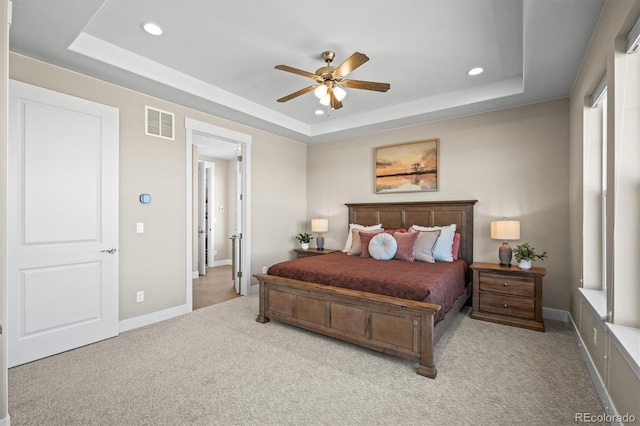 carpeted bedroom featuring recessed lighting, visible vents, a tray ceiling, and baseboards