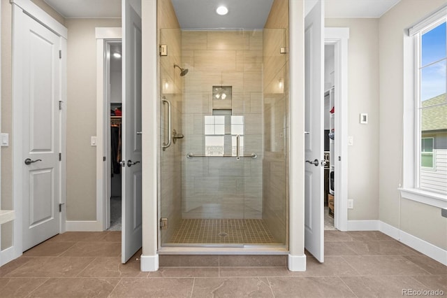 full bath featuring a spacious closet, baseboards, a stall shower, and tile patterned flooring