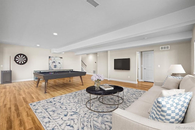 living room featuring light wood finished floors, baseboards, visible vents, and stairs