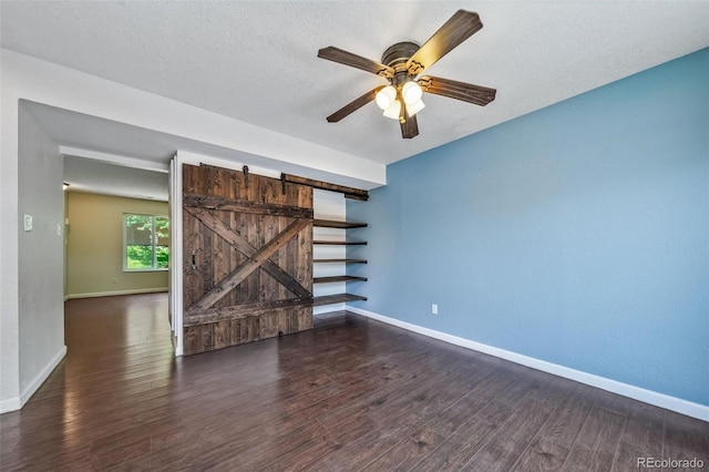 3806 S Yosemite St, Denver, CO 80237 - spare room with baseboards, wood finished floors, a barn door, a ceiling fan, and a textured ceiling