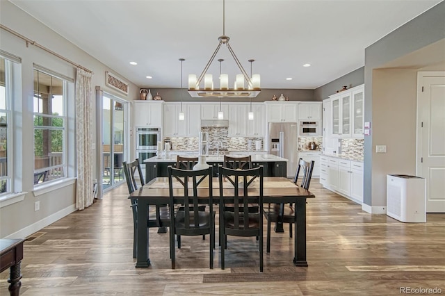15804 Elizabeth Cir E, Thornton, CO 80602 - dining room with wood finished floors, a chandelier, baseboards, and recessed lighting