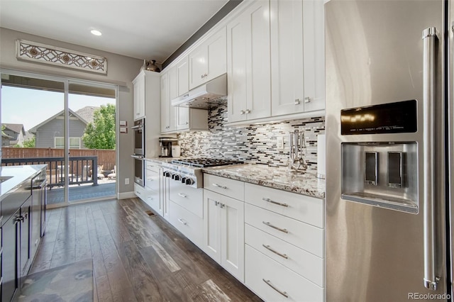15804 Elizabeth Cir E, Thornton, CO 80602 - kitchen with stainless steel appliances, under cabinet range hood, dark wood-type flooring, white cabinets, and tasteful backsplash