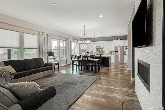 15804 Elizabeth Cir E, Thornton, CO 80602 - living area with plenty of natural light, wood finished floors, a stone fireplace, a chandelier, and recessed lighting