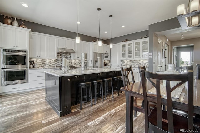 15804 Elizabeth Cir E, Thornton, CO 80602 - kitchen with stainless steel appliances, under cabinet range hood, light countertops, backsplash, and white cabinetry