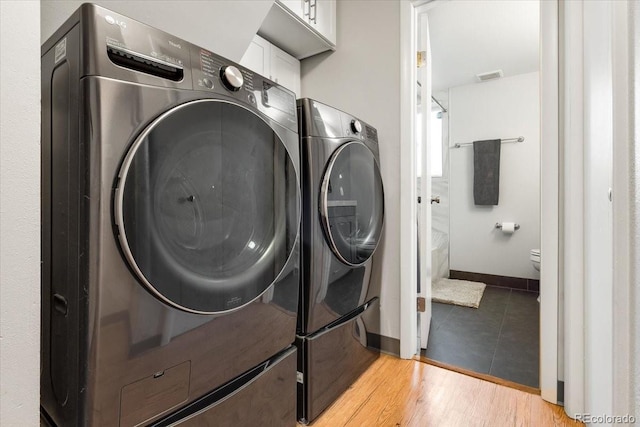 10833 W 61st Ave, Arvada, CO 80004 - laundry room featuring washer and dryer, cabinet space, and light wood-type flooring