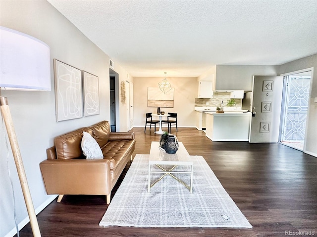 living area with dark wood finished floors, a textured ceiling, and baseboards