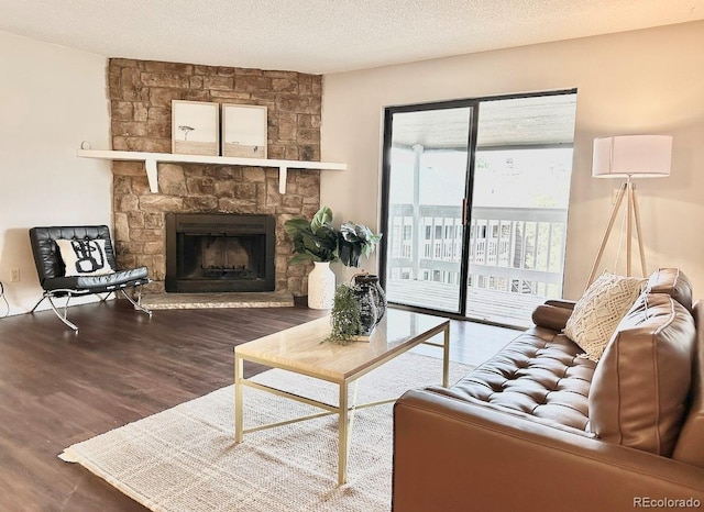 living area featuring wood finished floors, a stone fireplace, and a textured ceiling