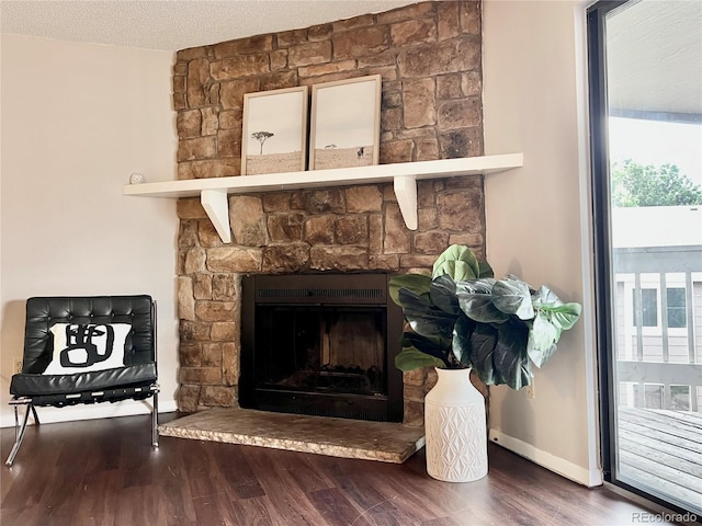 detailed view of wood finished floors, a stone fireplace, and baseboards