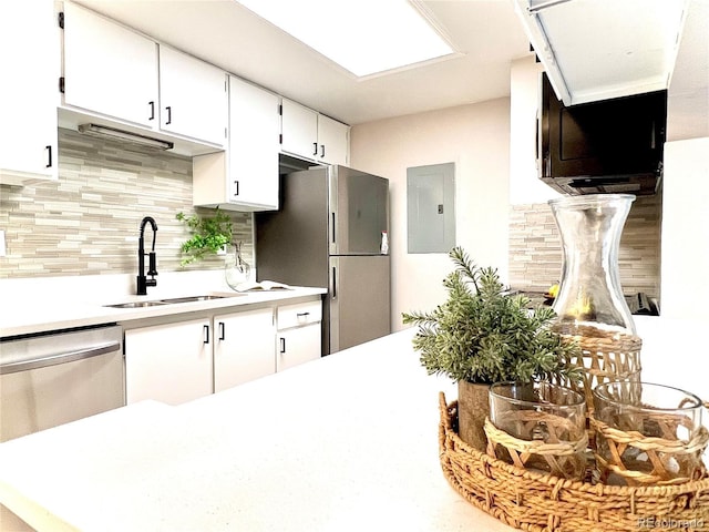 kitchen featuring a sink, electric panel, freestanding refrigerator, light countertops, and decorative backsplash