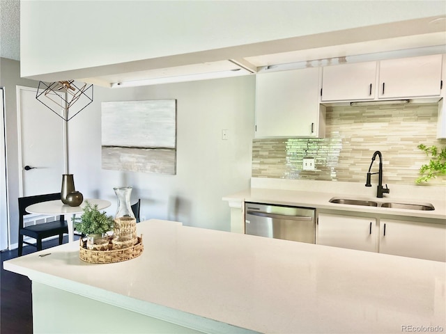 kitchen featuring a sink, stainless steel dishwasher, light countertops, decorative backsplash, and white cabinetry