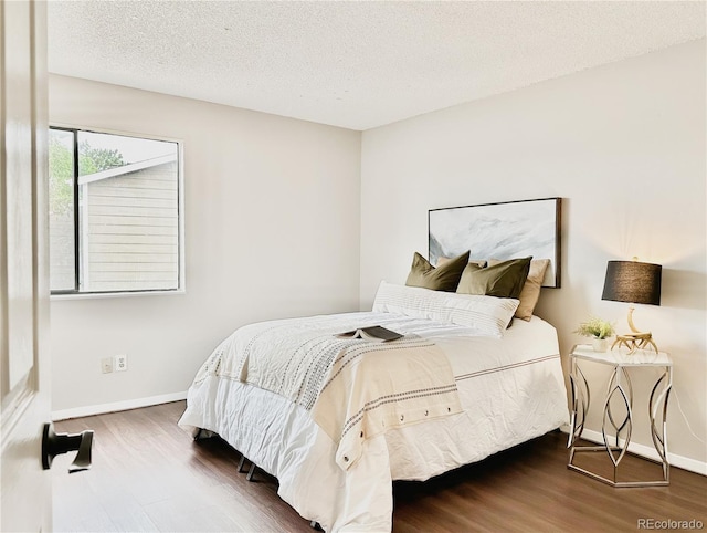 bedroom with wood finished floors, baseboards, and a textured ceiling