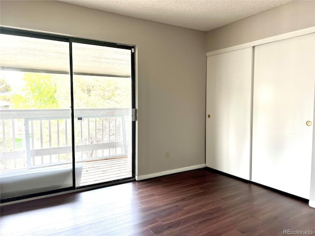 unfurnished bedroom featuring dark wood-type flooring, a closet, a textured ceiling, and baseboards