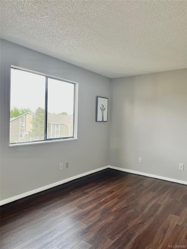 empty room with wood finished floors, a textured ceiling, and baseboards