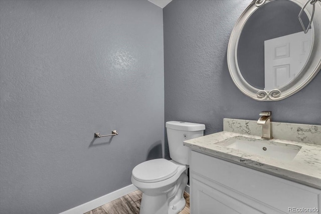 5286 Rustic Ave, Firestone, CO 80504 - half bathroom with wood finished floors, vanity, toilet, baseboards, and a textured wall