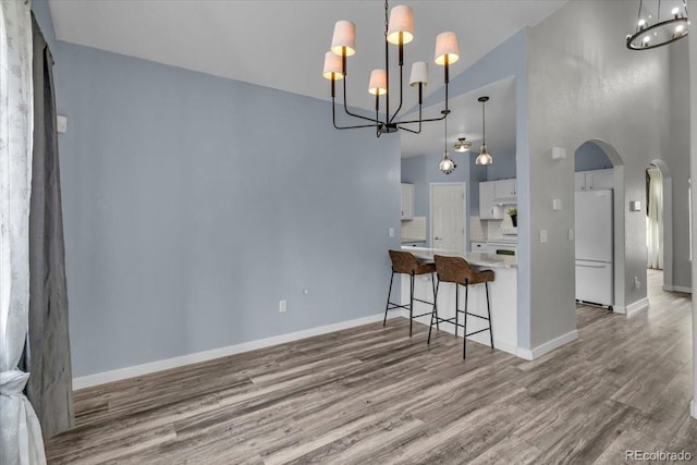 5286 Rustic Ave, Firestone, CO 80504 - kitchen with freestanding refrigerator, a chandelier, arched walkways, white cabinets, and high vaulted ceiling