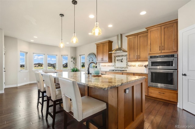 5954 Black Lion Ct, Windsor, CO 80550 - kitchen featuring wall chimney range hood, stainless steel appliances, brown cabinets, dark wood-style floors, and a sink