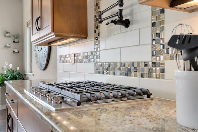 5954 Black Lion Ct, Windsor, CO 80550 - kitchen view of stainless steel gas stovetop, brown cabinets, decorative backsplash, and pot filler