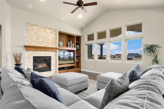 5954 Black Lion Ct, Windsor, CO 80550 - living room featuring a ceiling fan, wood finished floors, a fireplace, high vaulted ceiling, and baseboards