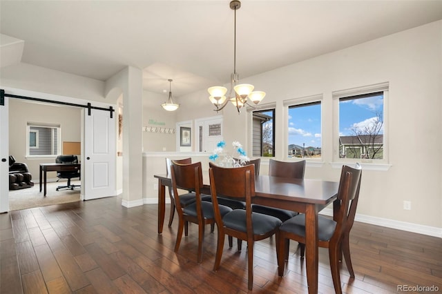 5954 Black Lion Ct, Windsor, CO 80550 - dining room featuring a barn door, dark wood-type flooring, baseboards, and a chandelier
