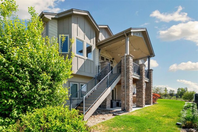 5954 Black Lion Ct, Windsor, CO 80550 - back of house featuring board and batten siding, a yard, and stairway