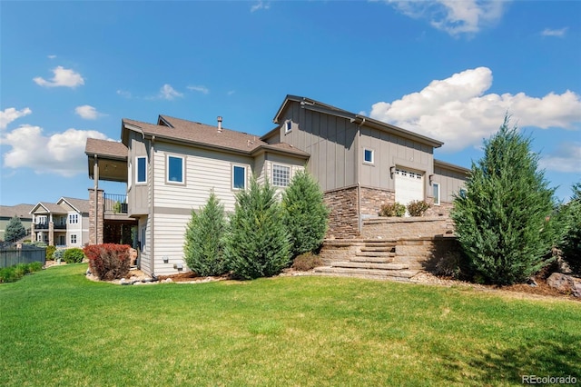 5954 Black Lion Ct, Windsor, CO 80550 - back of property with board and batten siding, an attached garage, and a lawn