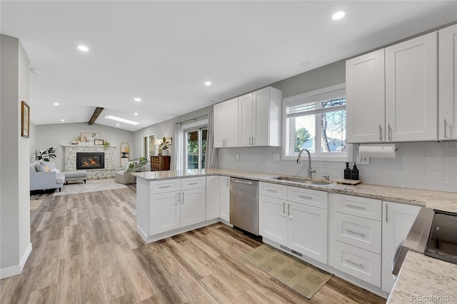 kitchen featuring dishwasher, a fireplace, light wood-style floors, white cabinets, and a sink