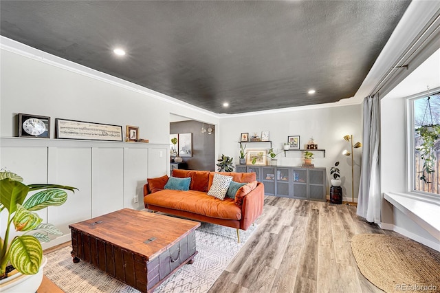 living room with crown molding, a decorative wall, recessed lighting, and wood finished floors