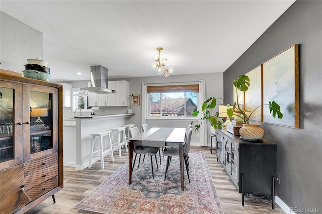 dining area featuring baseboards, light wood-type flooring, and a chandelier