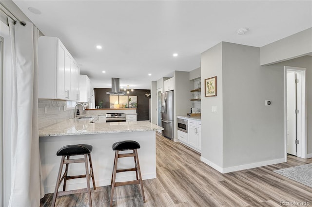 kitchen featuring oven, a peninsula, stainless steel fridge with ice dispenser, island range hood, and decorative backsplash