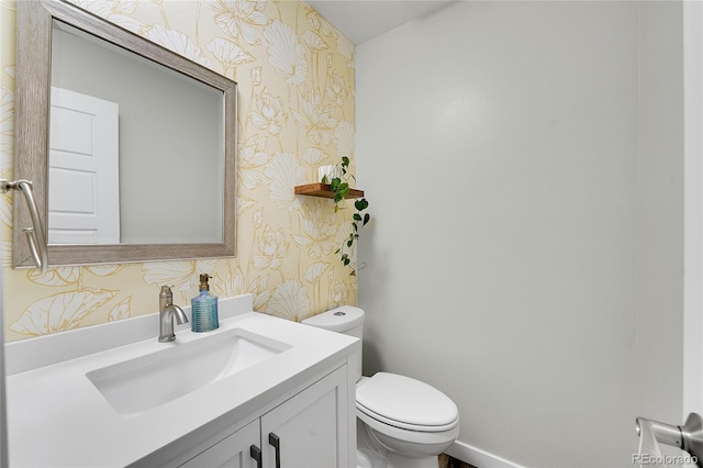 bathroom featuring wallpapered walls, toilet, vanity, and baseboards