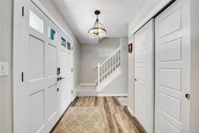 entrance foyer featuring stairway, baseboards, and wood finished floors