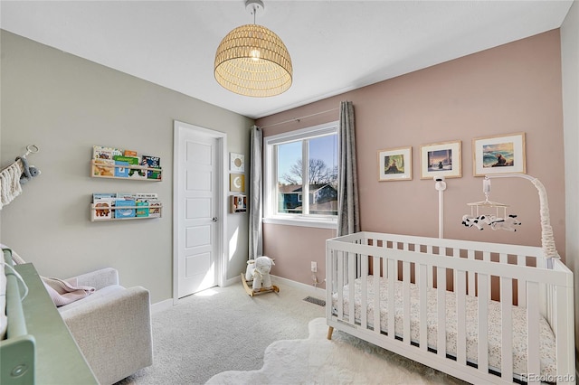 bedroom featuring visible vents, a crib, baseboards, and carpet floors