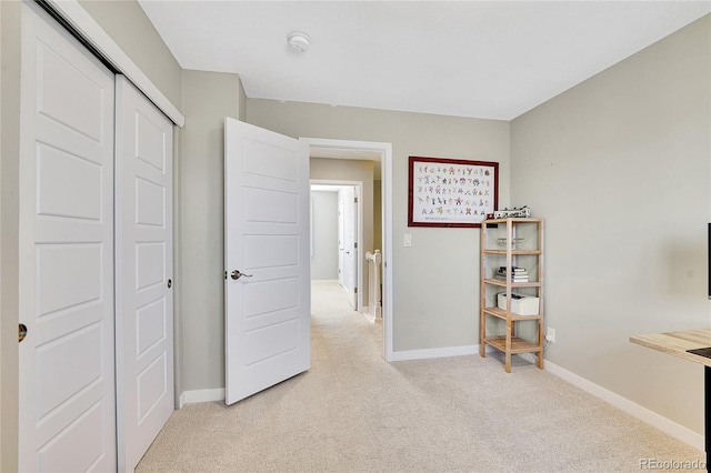 unfurnished bedroom featuring baseboards, light carpet, and a closet