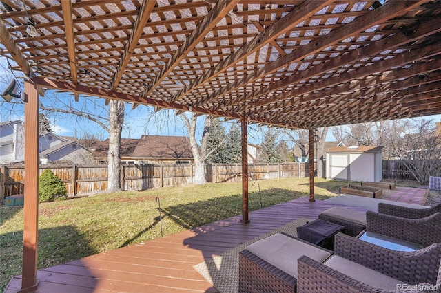 wooden terrace with a shed, a lawn, outdoor lounge area, a fenced backyard, and an outbuilding