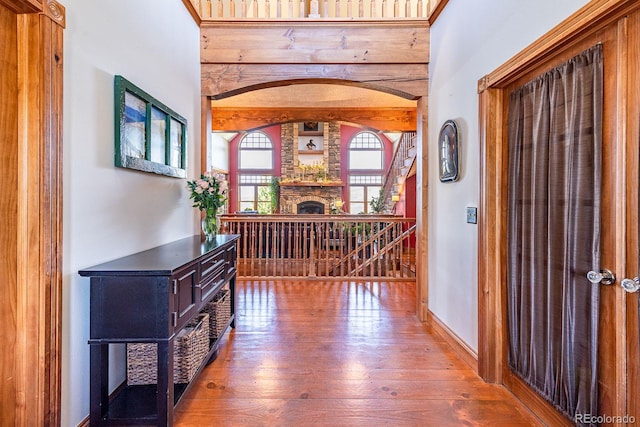 corridor featuring hardwood / wood-style floors, baseboards, and arched walkways