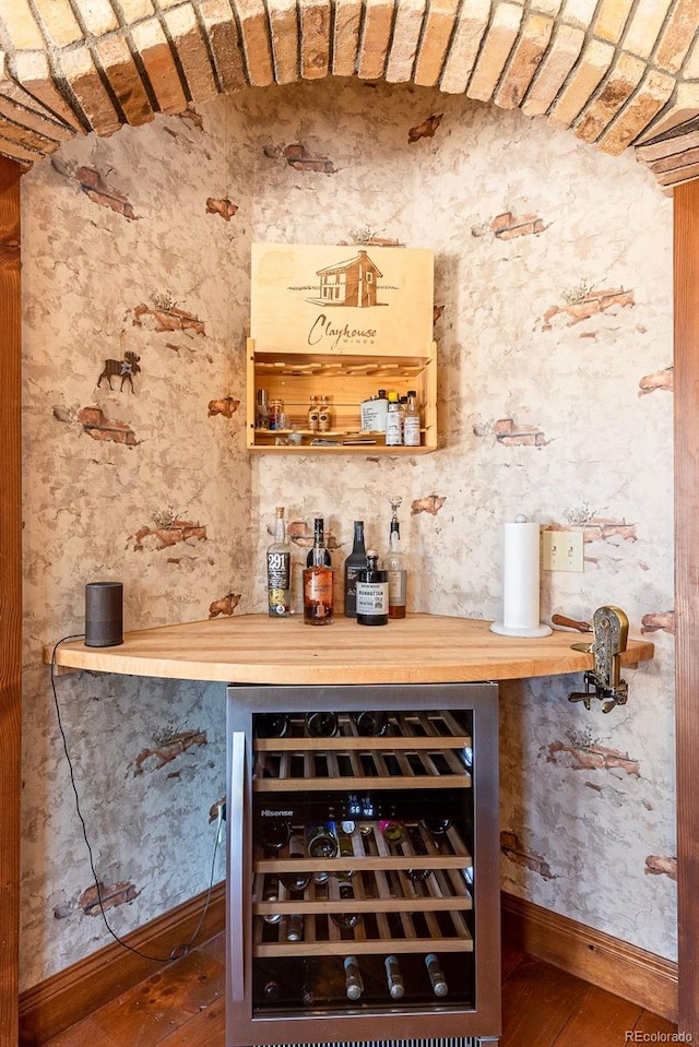 bar with baseboards, wine cooler, and a bar