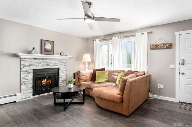 1391 Elmira St, Aurora, CO 80010 - living room with dark wood-style flooring, ceiling fan, a stone fireplace, and a baseboard radiator
